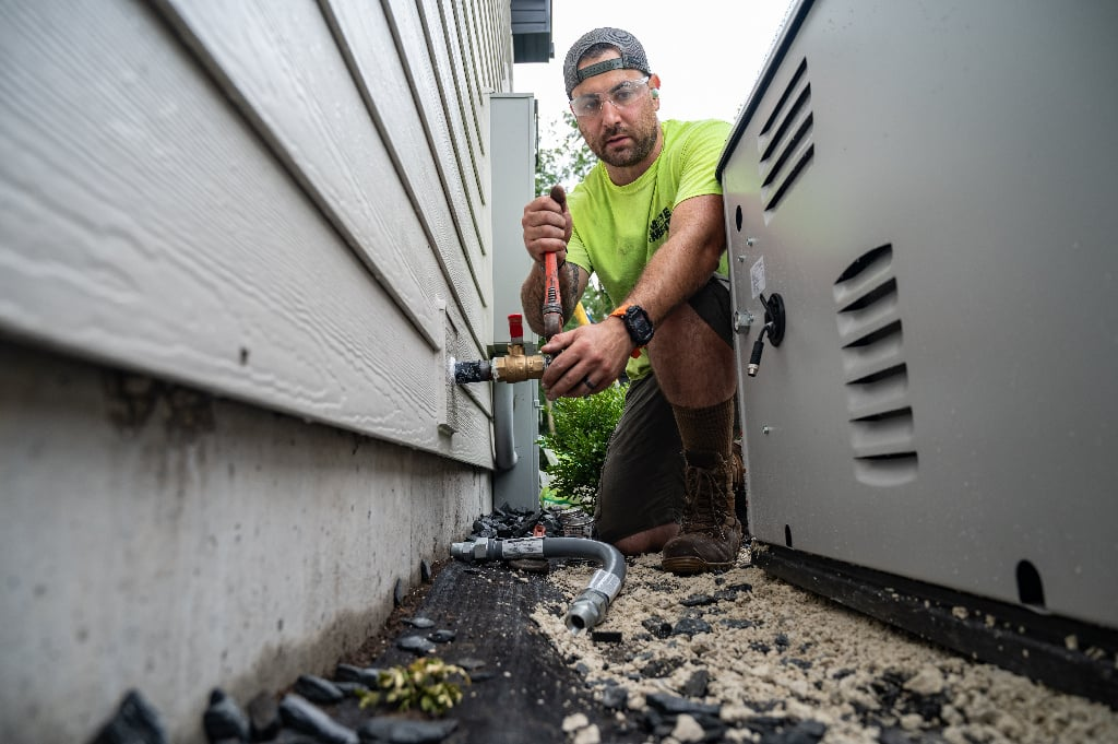 Technician working on piping beside a standby generator