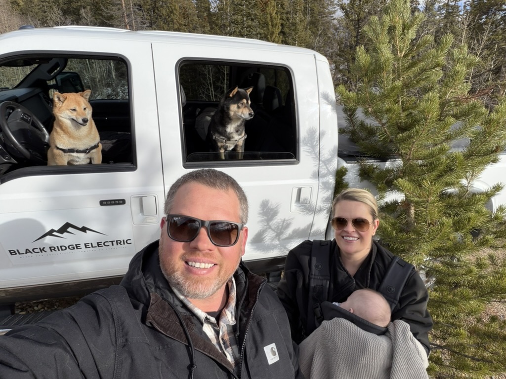 Black Ridge Electric family beside a company truck with two dogs