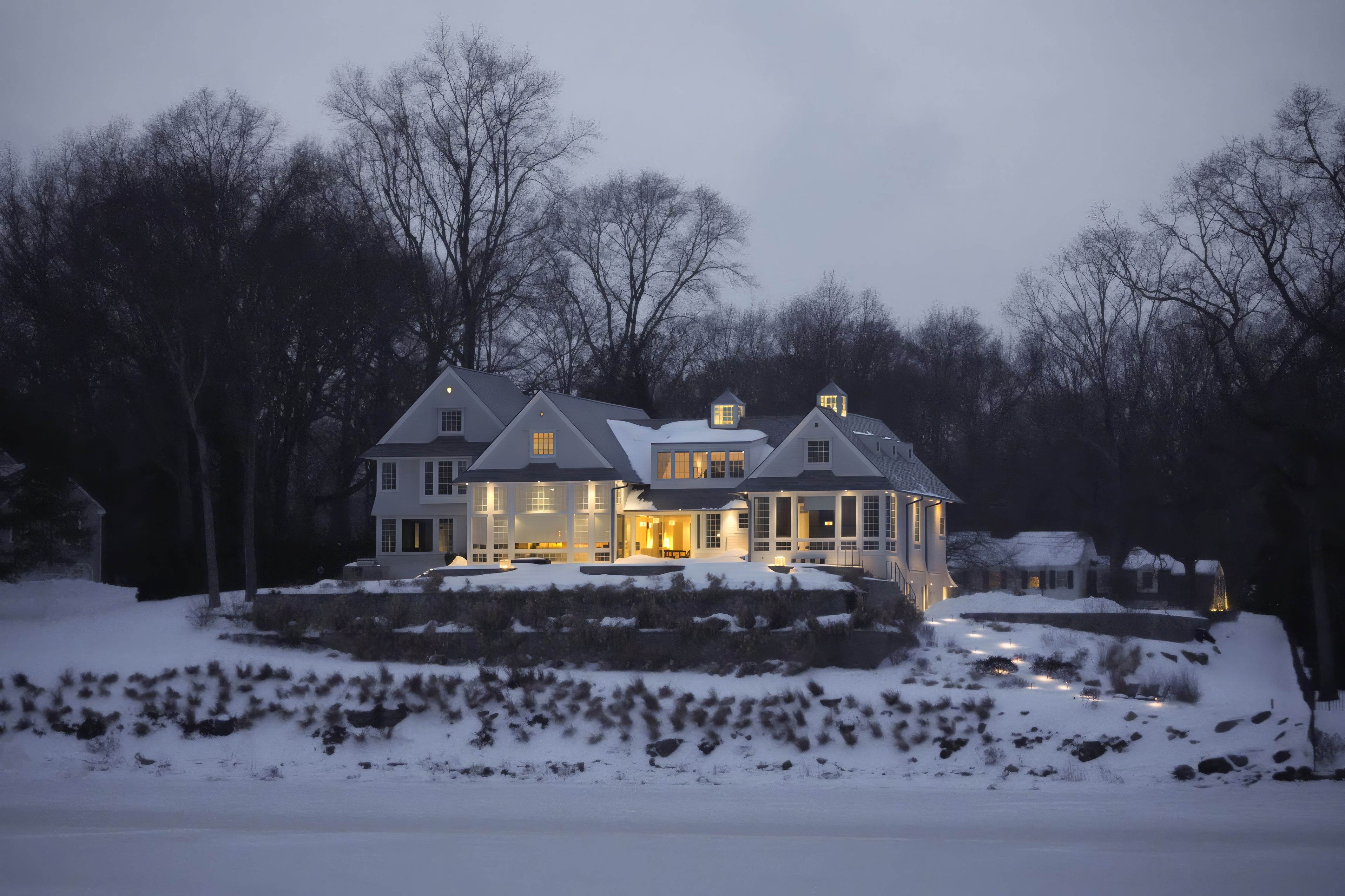A house with illuminated windows on a snowy winter evening.