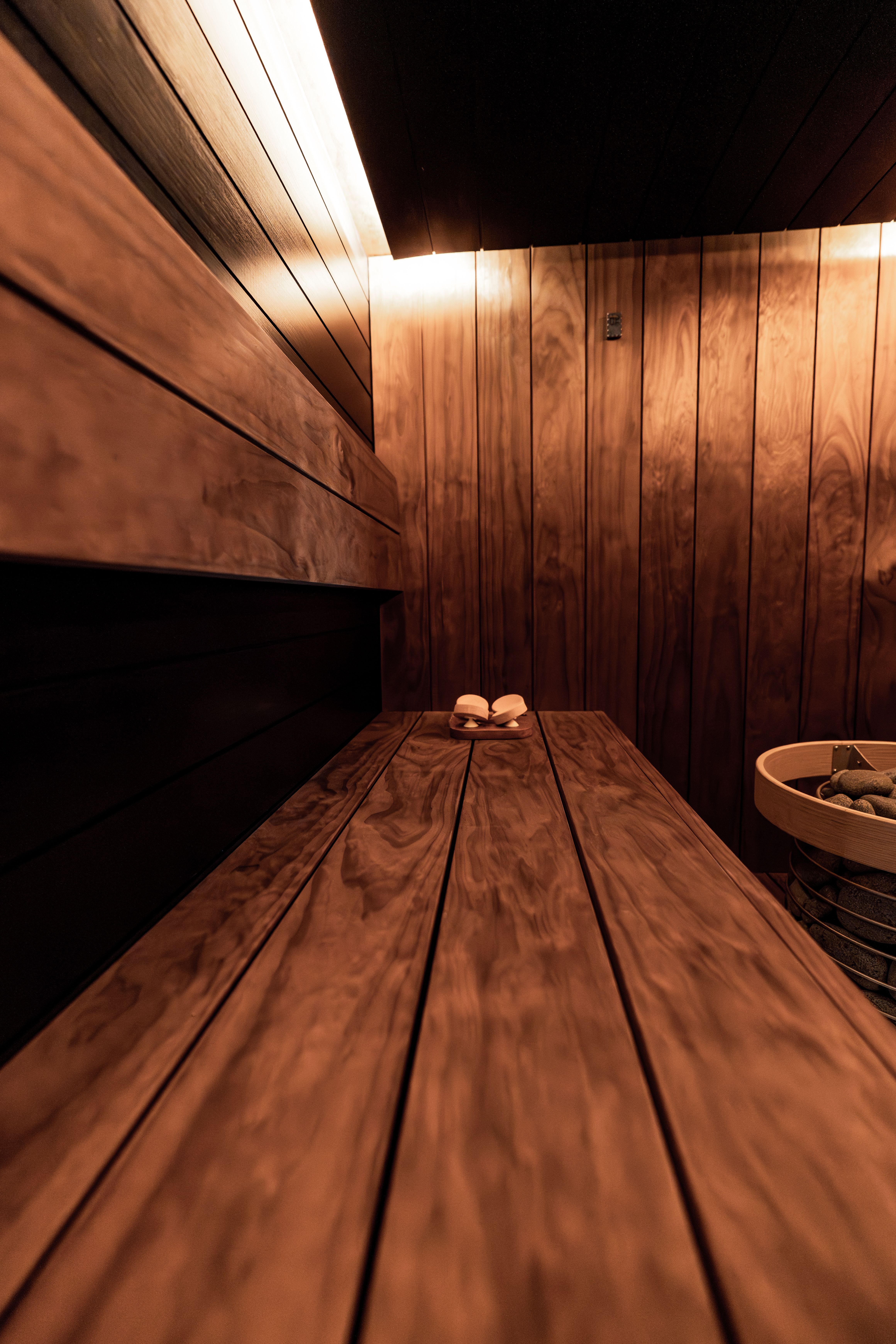 Wood-lined indoor sauna with a bench and stone-filled heater.